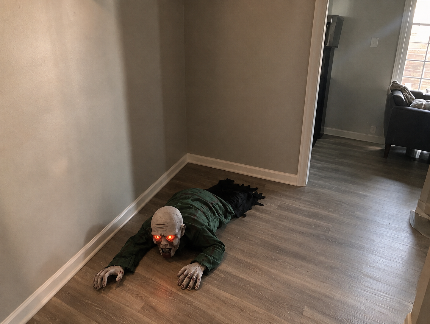 Crawling Zombie Prop with glowing red eyes dragging itself across a home hallway floor